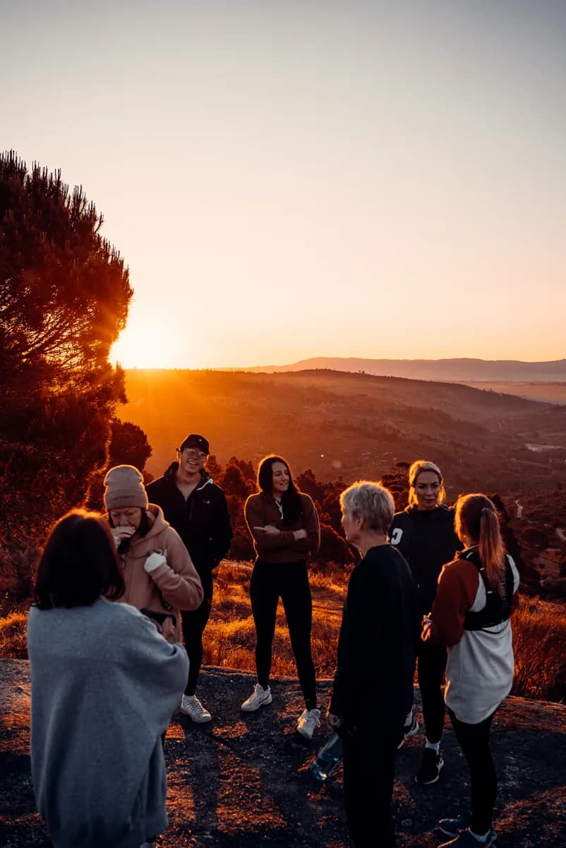 Elysium Retreats guests gathered on a hilltop at sunrise in Central Portugal, golden light streaming through pine trees