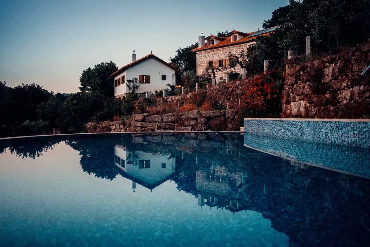 Infinity pool reflecting the stone villas of Quinta do Rabaçal at dusk, Central Portugal