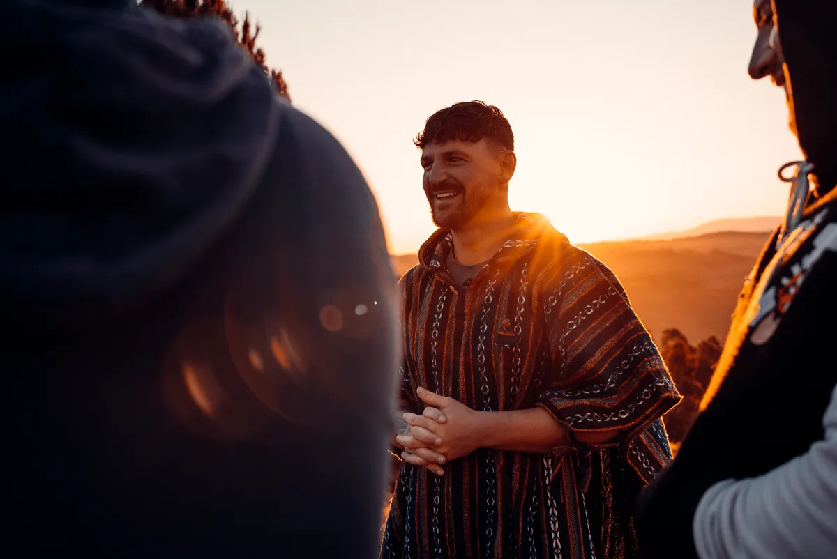 Tommy Napolitano speaking to the group at sunset, backlit by golden light on a Portuguese hilltop