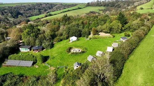 Aerial view of the retreat field with geodesic dome, cabins, and valley stretching beyond