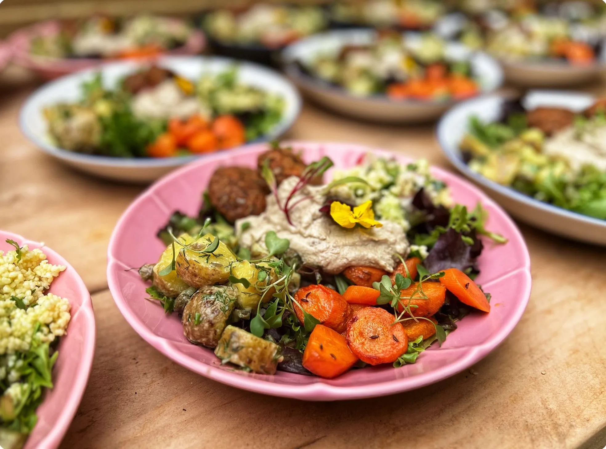 Colourful buddha bowl with roasted vegetables, hummus, and edible flowers