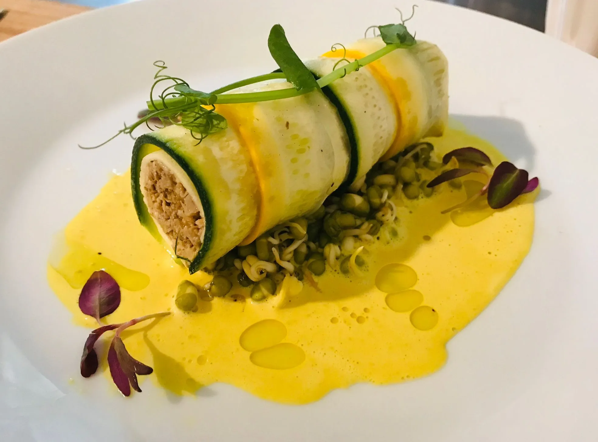 Zucchini cannelloni with saffron sauce, sprouted lentils, and microgreens